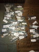 Multiple labeled ziplock bags containing foreign coins from countries including Mexico, Malawi, Mali, Morocco, Hungary, Nigeria, Philippines, Poland, Spain, Turkey, Vietnam, Yugoslavia, Zimbabwe among others, placed on a wooden surface.