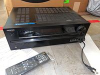 Front and top view of Onkyo HT-R590 AV receiver with remote control in front.