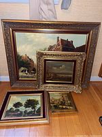 Overview of six framed oil paintings on wood floor background
