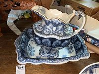 Photo showing the pitcher resting inside the basin, both decorated with detailed blue and white floral/scroll patterns.