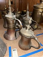 Photo showing an arrangement of the four metal pitchers from a side angle highlighting their heights and lid details.