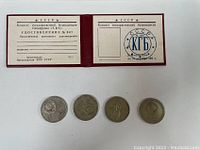 Four Soviet 1 Ruble coins and the blank KGB identity card laid out next to each other to show lot contents.