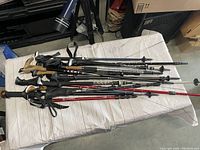 Photo showing multiple hiking walking sticks and trekking poles laid out on a cushioned surface.
