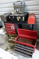 View of assorted metal tool chests, toolboxes, and table stacked and arranged together