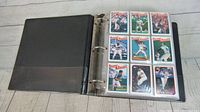 Black three-ring binder open showing baseball cards in plastic sleeves. Front sides of various 1988 Topps Record Breaker cards with player images and titles.