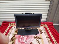 Sony FWD-32LX2F 32-inch LCD flat wide display monitor resting on a floral patterned cloth with a red border. View shows front screen and black stand base.
