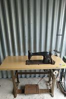 Full view of the vintage Singer sewing machine mounted on wooden table with metal framework and pedal.