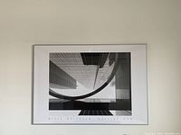 Photo of the framed black and white architectural print showing buildings with glass and concrete surfaces, featuring a unique curve of a building in the composition.