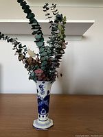 Photo of dried floral arrangement in a blue and white porcelain vase, showing eucalyptus and dried hydrangea flowers.