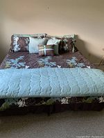 King size bed made with floral patterned bedding and multiple pillows, showing front view.