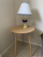 Lamp with blue glass accent on light wood round side table