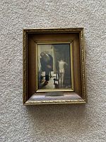 Photo of a small framed art print reproduction of Magritte's 'Not to Be Reproduced'. The frame is ornate with a gold-bronze finish and features an engraved title plaque.