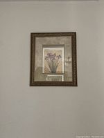 Photo of framed botanical print of purple irises with beige mat and ornate brown frame