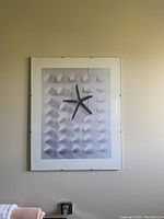 Framed black and white print of starfish and shell pattern hanging on wall