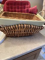 Photo shows a rectangular wicker basket with a green SPA cushion inside placed on a countertop.