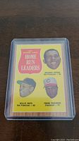 Front of 1962 Topps baseball card showing Willie Mays, Frank Robinson, Orlando Cepeda with home run totals and team names, in protective sleeve.