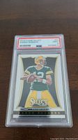 2013 Panini Select Aaron Rodgers card graded PSA 9 Mint showing a quarterback in uniform ready to throw the ball in Packers green and yellow.