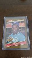 Photo of Bo Jackson rookie card from 1990 Donruss Highlights series in protective plastic sleeve on wooden surface.