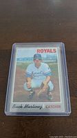 Front view of Buck Martinez rookie baseball card in protective plastic case, showing player in Royals uniform.