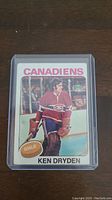 Front of Ken Dryden hockey card, showing player in Canadiens goalie gear with team name and goalie badge.