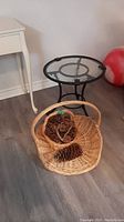 Photo of small and large wicker baskets along with small round glass top patio table on floor