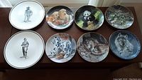 All eight plates displayed on a table showing designs including animals and hunters