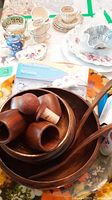 Photo showing wood salad bowls, wooden napkin rings, salad spoon and fork, ceramic demitasse cups and saucers, small decorative dishes and plates.