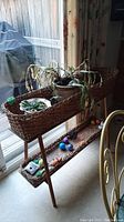 Side view of wicker plant stand, showing woven wicker shelves and wooden legs beside sliding glass door with items on shelves.