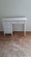 Front view of a white wooden vanity desk with one drawer across the opening for seat and three drawers stacked on left side.