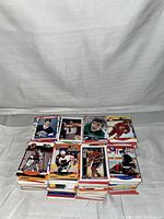 Stack of hockey cards in multiple piles on a white cloth background, showing some cards from different decades and players in various uniforms.