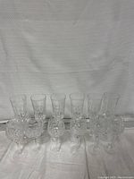 Front view of the set showing all 12 stemware glasses upright, highlighting decorative etched patterns on bowls and ribbed round bases.