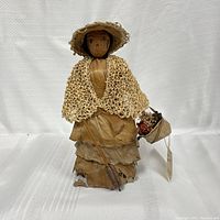 Full frontal view of the handmade Bermuda doll showing crafted hat, shawl, layered dress, and face details.