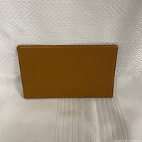 Front exterior of the brown genuine leather cardholder and checkbook holder showing smooth pebbled texture.