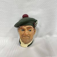Front angle view of the Bosson chalkware head showing facial details and green tam o' shanter hat with red pompom and floral decoration.