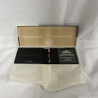 Photo of the vintage Buxton wallet inside the original box with tissue paper, wallet partially visible.