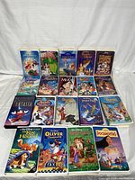 Front face view of 19 Disney VHS tapes in original cases arranged in 3 rows showing covers of the movies.