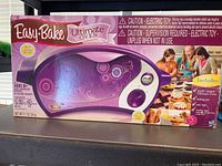 Original boxed Hasbro Easy Bake Ultimate Oven, purple and white, model name visible on box front.