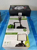 Vivitar LED video light in box with product image and key features visible, showing 120 LED lights and mounting options.