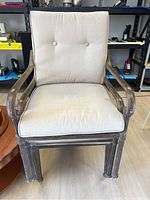 Single metal frame patio chair with cream cushion showing stained cushion and armrest detail