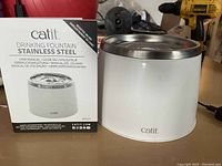 Photo showing Catit stainless steel cat drinking fountain alongside its original box and user manual.