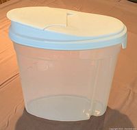 Single Rubbermaid container with white pourable spout lid, clear plastic body, standing on fabric surface.