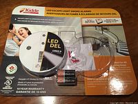 Front view of the Kidde LED Escape Light Smoke Alarm in original packaging, showing the product and key features.