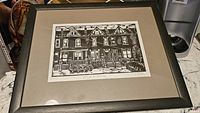 Framed limited edition lino cut print showing black and white townhouses in Hamilton, with detailed architectural lines.
