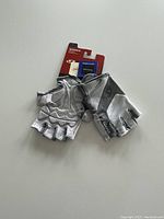 Pair of fingerless men's Monaco bike gloves in light grey and silver colors on white background. Gloves attached to original packaging card with 'Monaco' label visible.