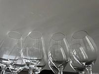Side view of eight clear crystal wine glasses grouped together showing bowl shape and stems.