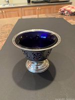 Front angle photo of the silver metal candy dish with dark blue removable glass bowl, showing filigree design on metal and shiny finish.
