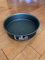 Photo of a black 9-inch diameter springform pan with a textured bottom and metal latch