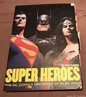 Front cover of the postcard set showing Superman, Batman and Wonder Woman with title 'Super Heroes - The DC Comics Universe of Alex Ross'