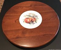 Top view of wooden lazy Susan showing the ceramic center insert with apple design.
