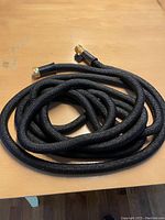Coiled black expandable garden hose with woven fabric outer covering.